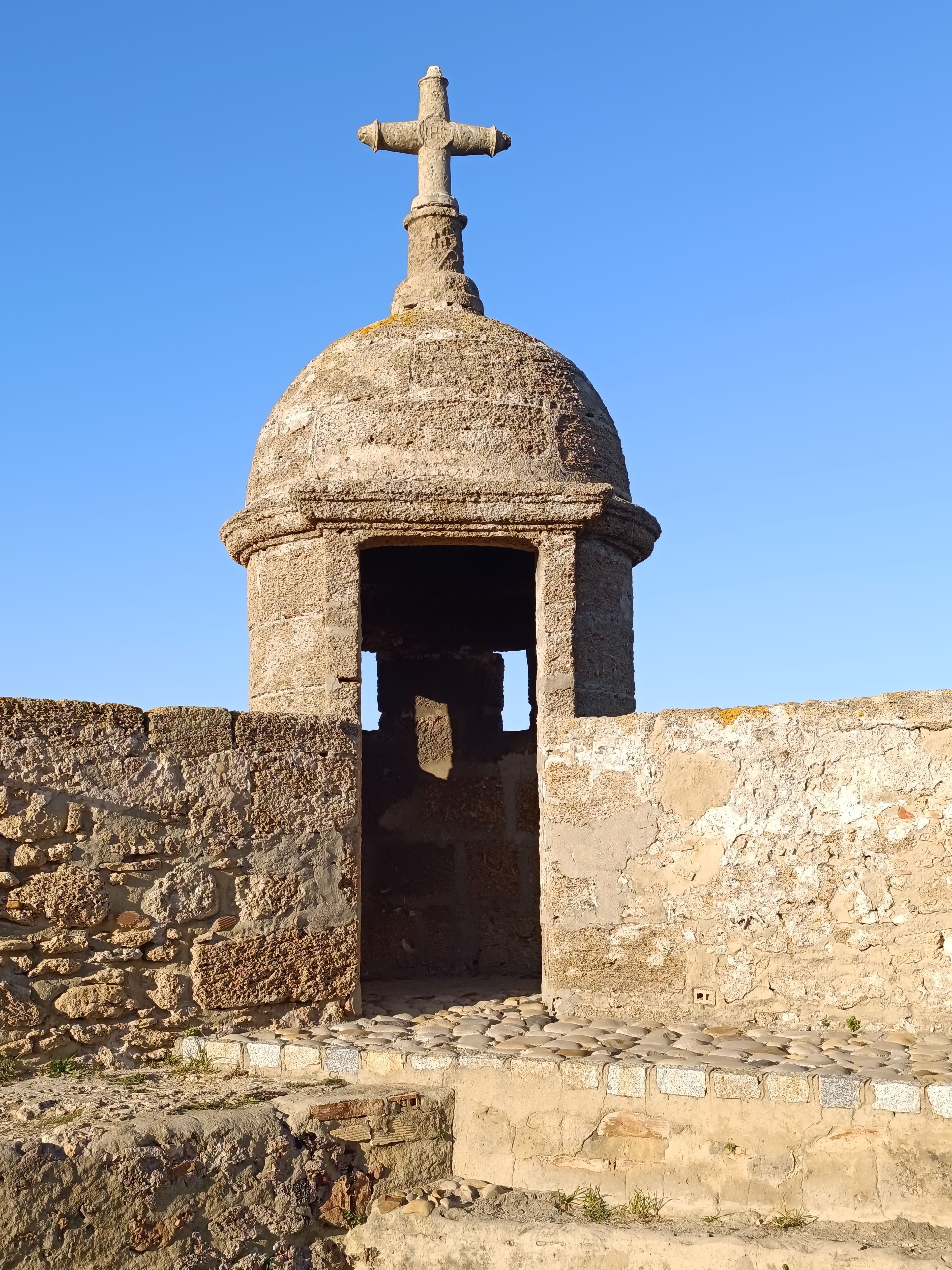 Stone wall and watchtower on the Spanish coast under a clear sky